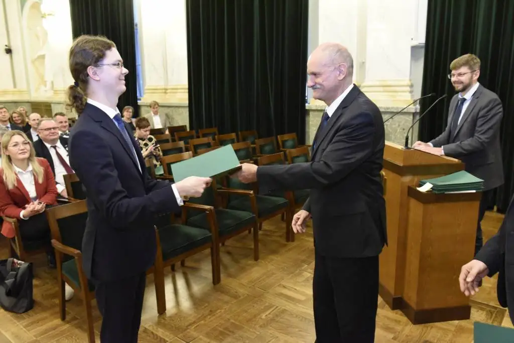 Lukasz-Salwik odbiera list gratulacyjny od Prorektora Wojciecha Łużnego