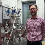 Prof. Witold Skowroński na tle systemu do nanoszenia cienkich warstw metodą rozpylania magnetronowego firmy Prevac. Aparatura będzie wykorzystywana m.in. w badaniach realizowanych w ramach projektu REMISPIN, dotyczącym mikrofalowych układów spintronicznych