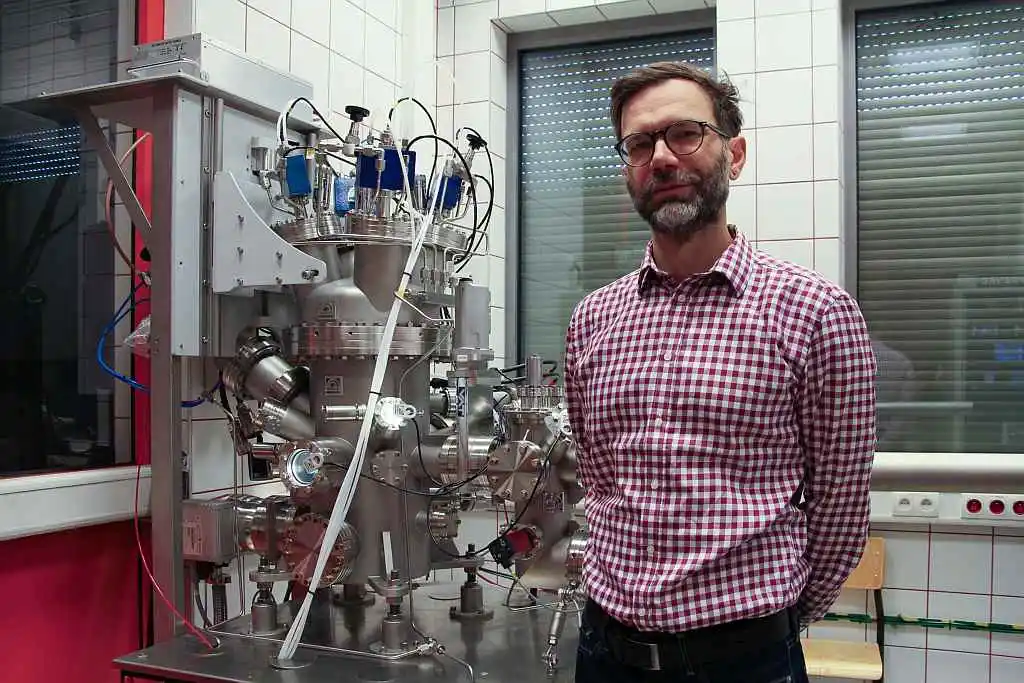 Prof. Witold Skowroński na tle systemu do nanoszenia cienkich warstw metodą rozpylania magnetronowego firmy Prevac. Aparatura będzie wykorzystywana m.in. w badaniach realizowanych w ramach projektu REMISPIN, dotyczącym mikrofalowych układów spintronicznych
